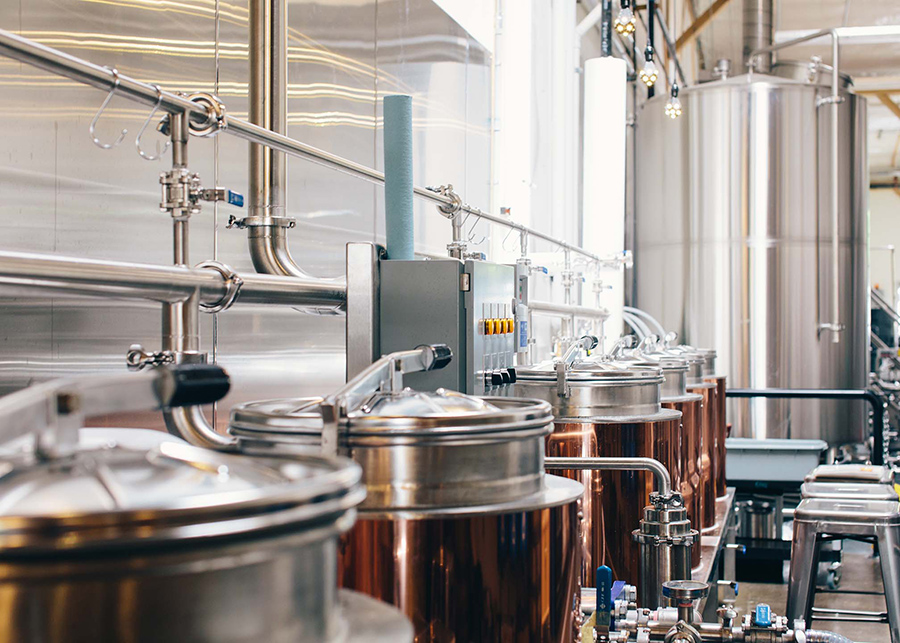 The brewing station, copper-plated distilling tanks sit in the foreground, behind them massive stainless steel holding tanks